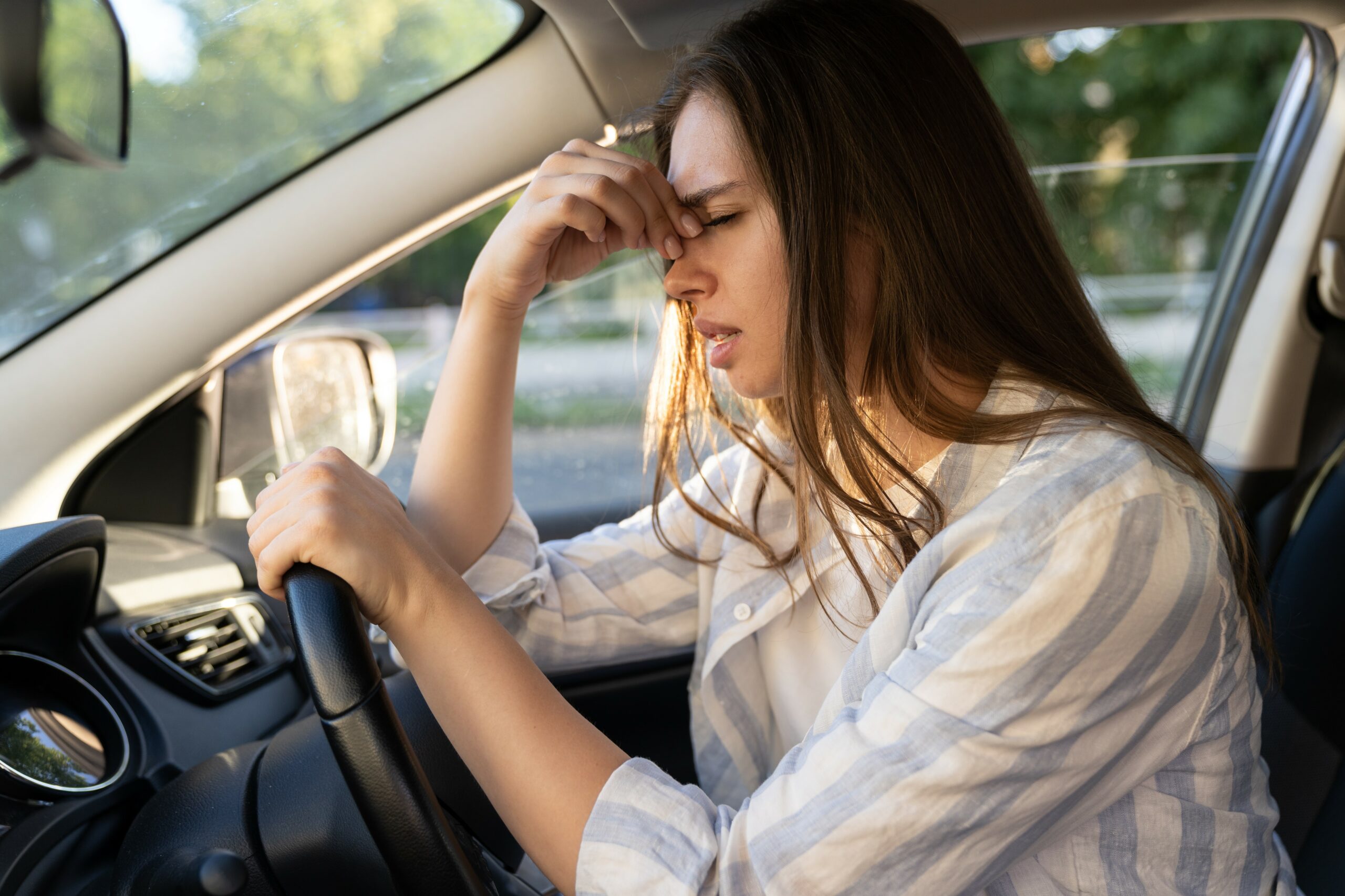 Tired young woman car driver suffer from headache or migraine pain inside vehicle touch forehead