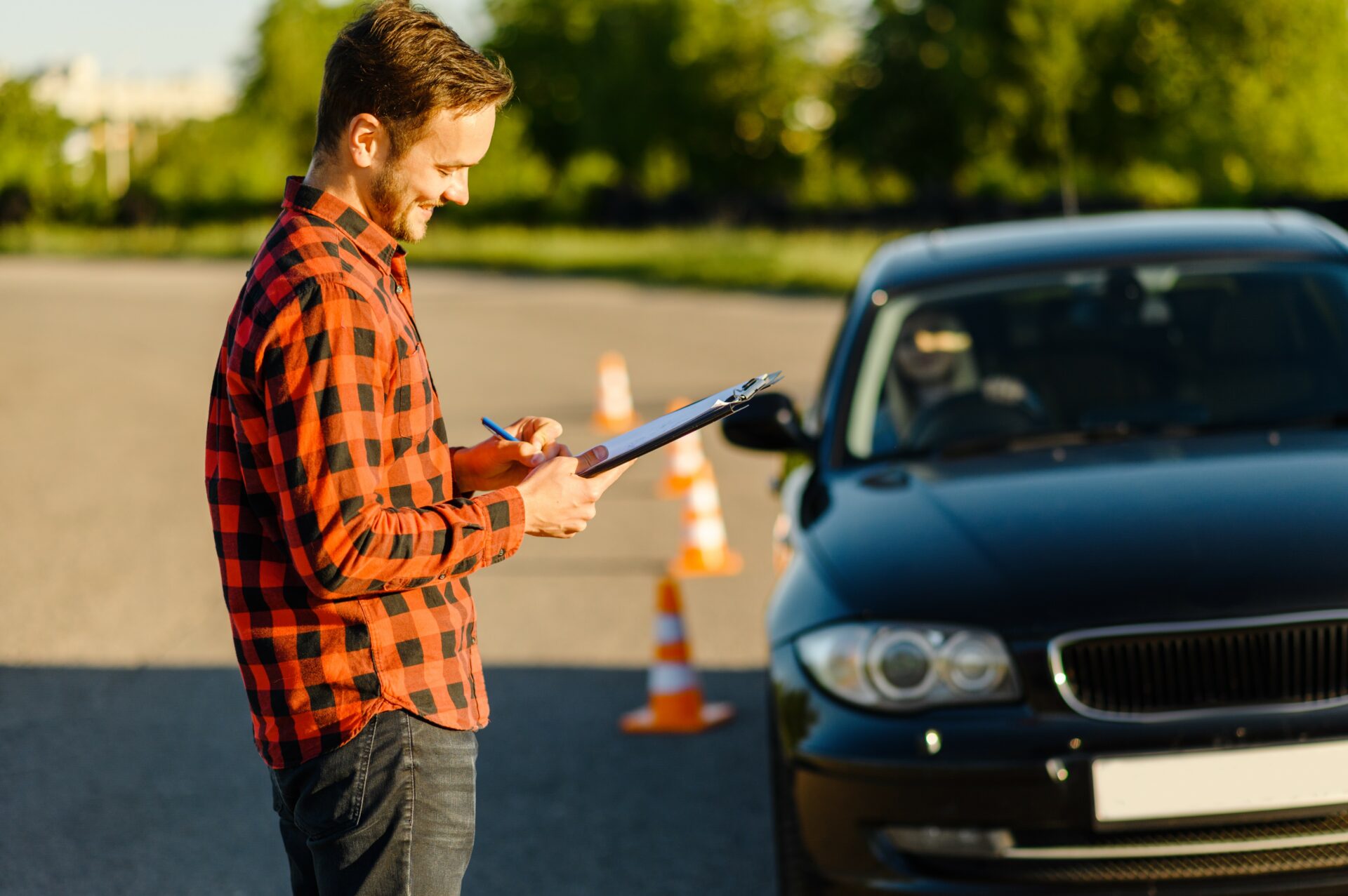 Male instructor and woman in car, traffic cones, lesson in driving school. Man teaching lady to drive vehicle. Driver's license education