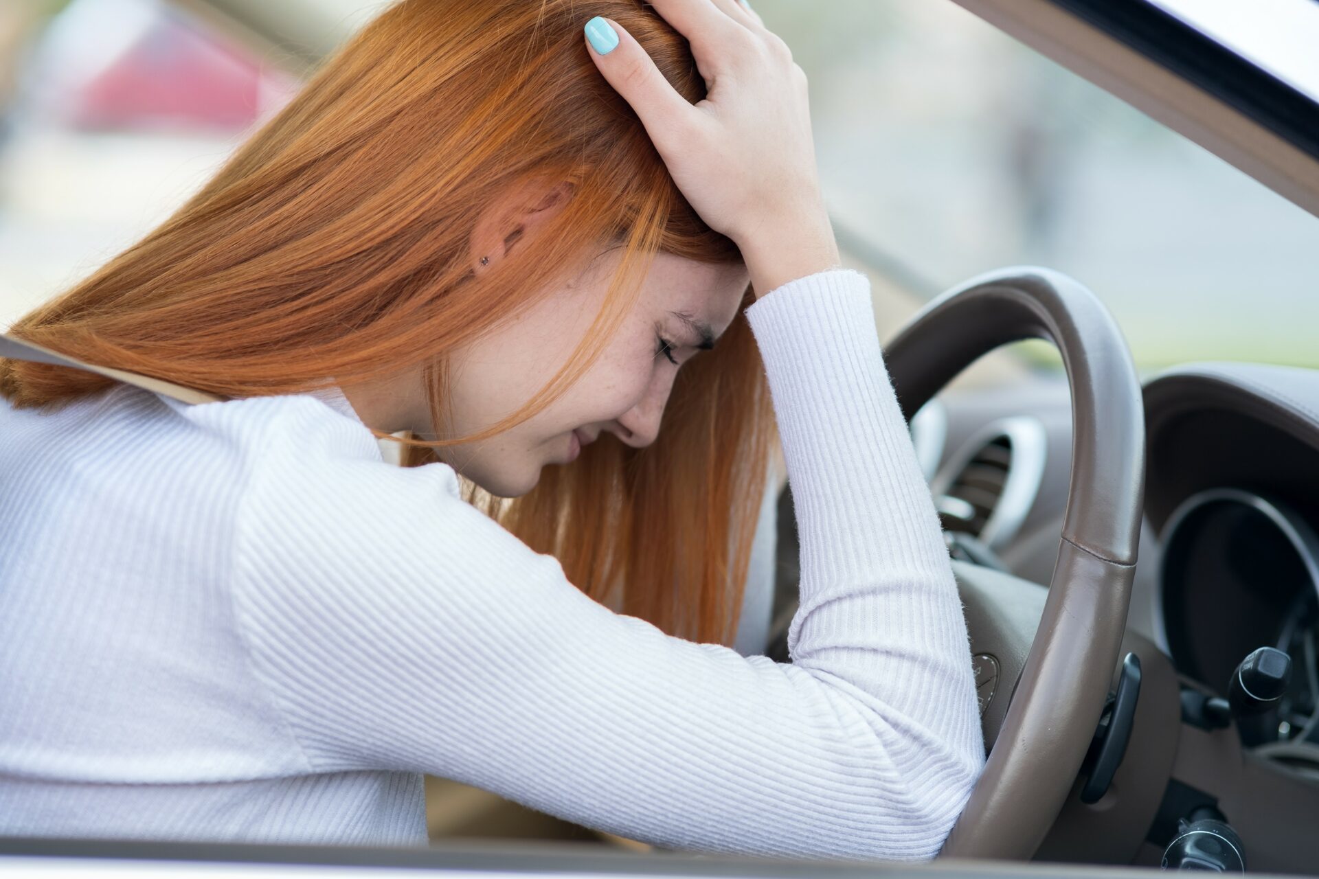 Sad tired yound woman driver sitting behind the car steering wheel in traffic jam.