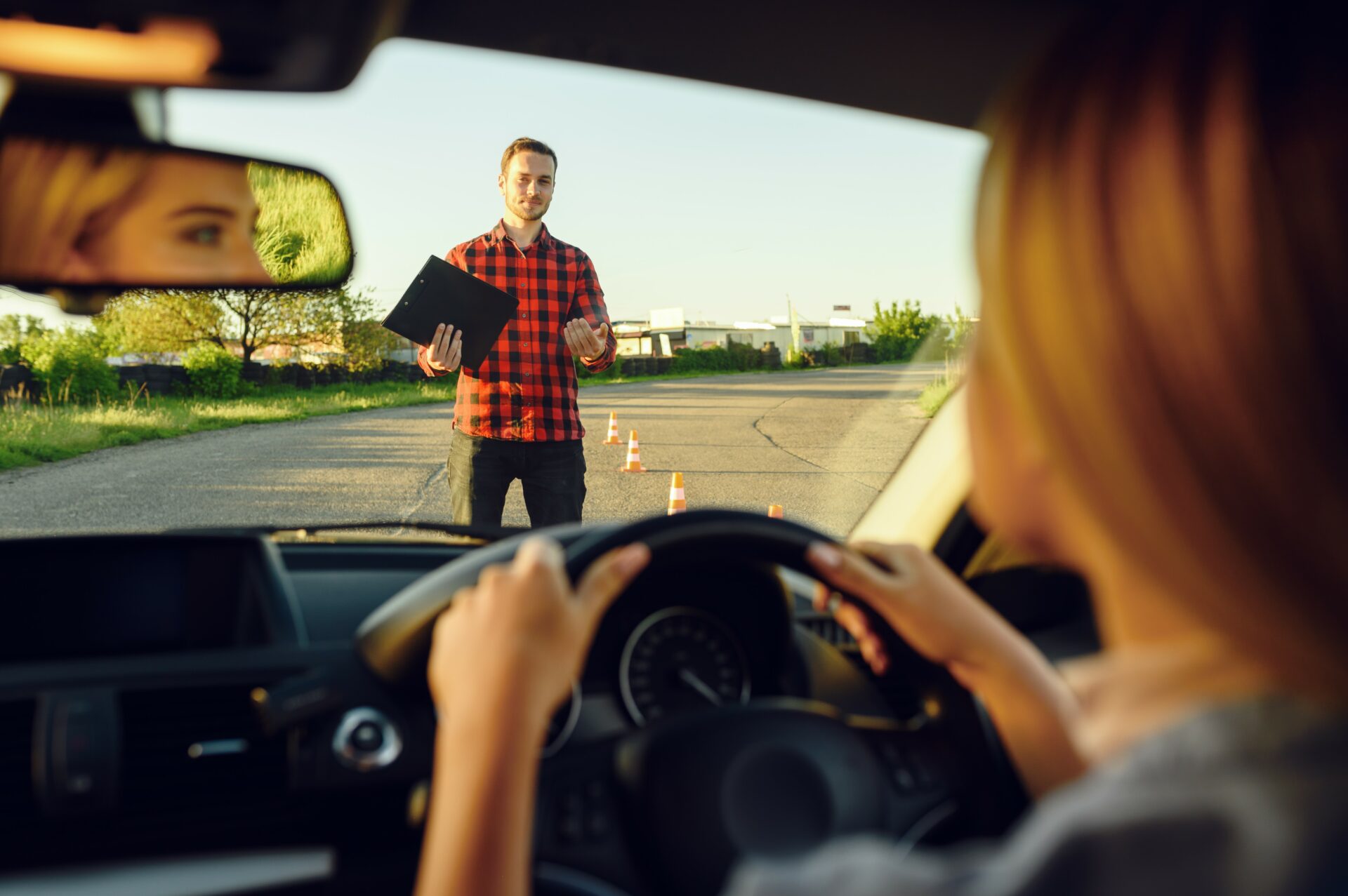 Woman in the car, instructor with checklist on road, driving school. Man teaching lady to drive vehicle. Driver's license education
