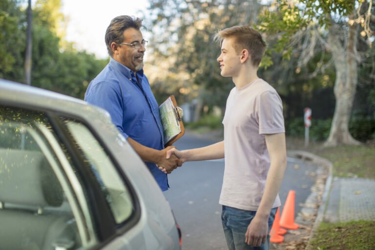 learner-driver-and-instructor-shaking-hands-at-car-2022-12-16-22-33-46-utc-768x512